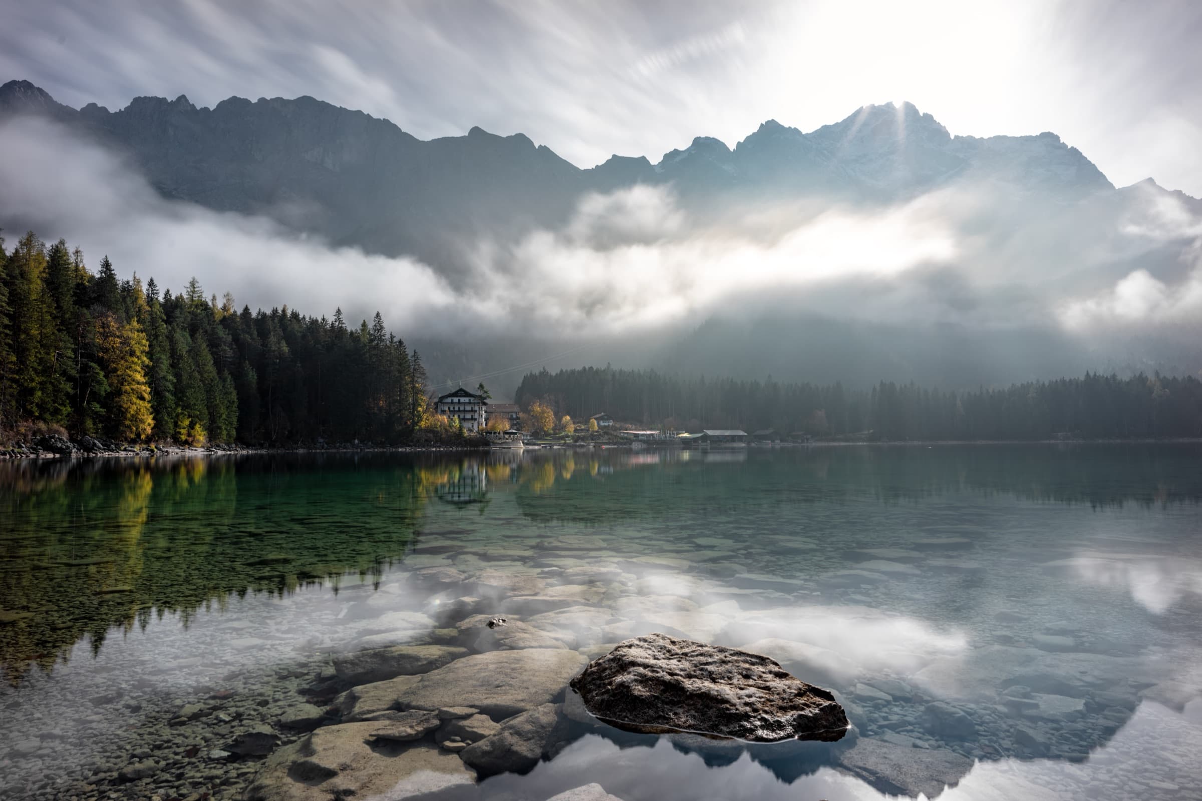Mist lifting off a still mountain lake at dawn